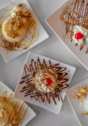 Assorted gourmet ice cream sundaes with toppings and sauces.